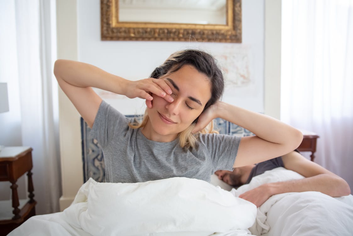 Adult performing gentle morning stretches beside their bed